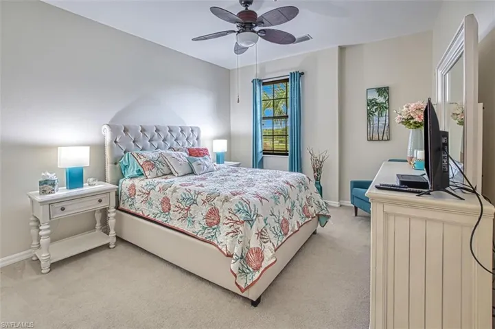Bedroom featuring light colored carpet, baseboards, and ceiling fan