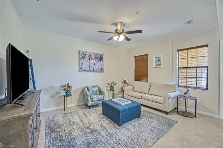 Living area with light tile patterned flooring, ceiling fan, and baseboards