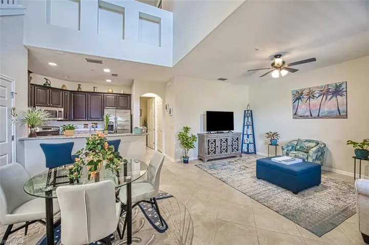 Living room featuring arched walkways, a ceiling fan, baseboards, light tile patterned flooring, and recessed lighting