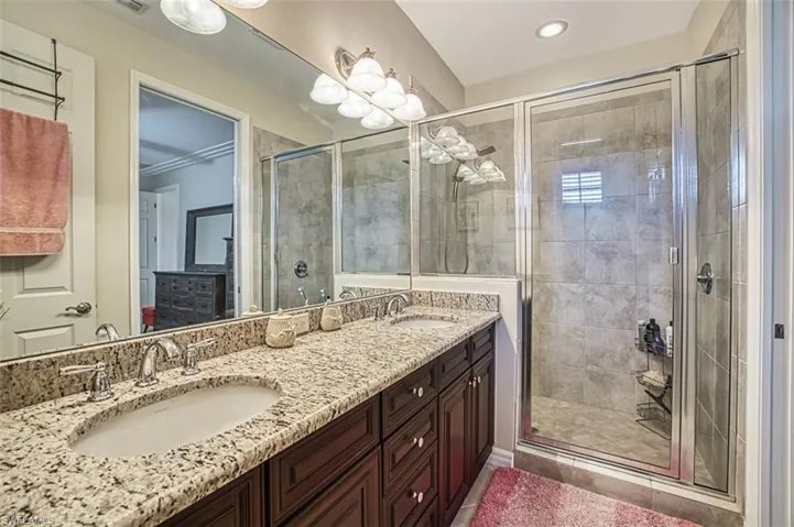 Bathroom with a shower stall, double vanity, recessed lighting, and ornamental molding