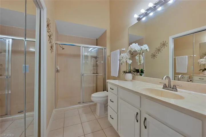 Bathroom with toilet, vanity, tile patterned floors, and walk in shower