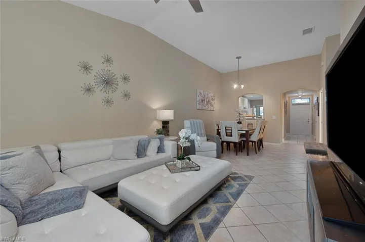 Living room featuring ceiling fan, light tile patterned flooring, and high vaulted ceiling