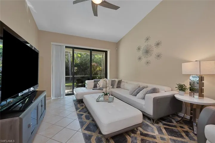 Tiled living room with ceiling fan and high vaulted ceiling
