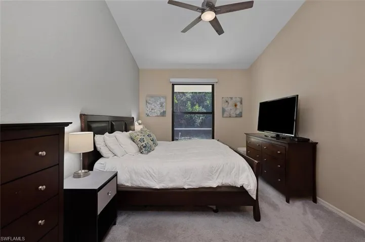 Primary Bedroom featuring ceiling fan, light carpet, and vaulted ceiling