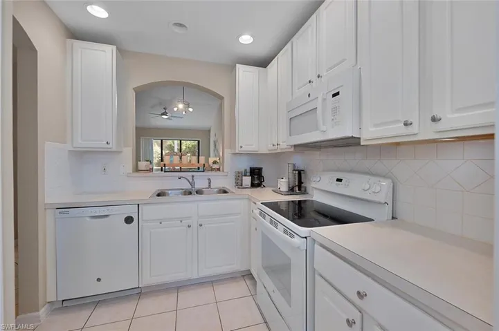 Kitchen with white cabinets, white appliances, ceiling fan, and sink