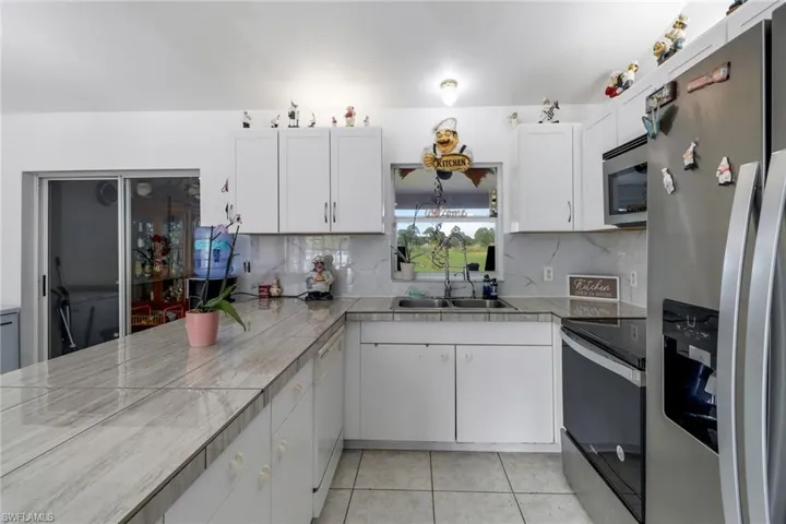 Kitchen with appliances with stainless steel finishes, white cabinetry, and tasteful backsplash