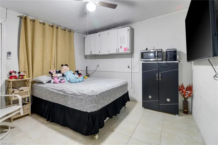 Tiled bedroom featuring ceiling fan