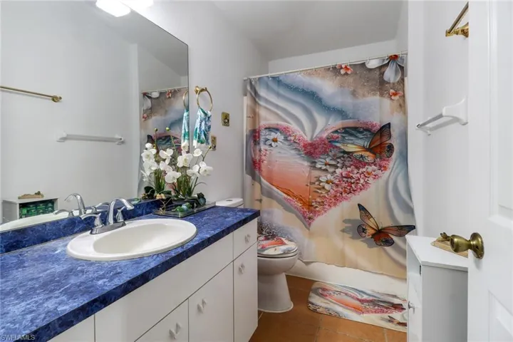Bathroom with vanity, curtained shower, toilet, and tile patterned flooring