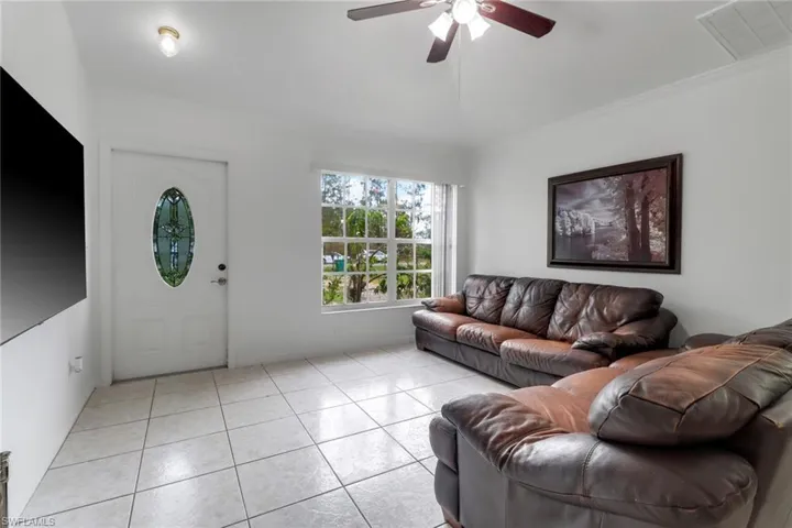 Tiled living room featuring crown molding and ceiling fan