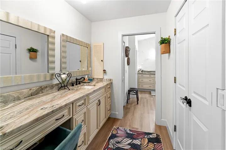 Vanity with light-colored cabinetry and a varied stone countertop