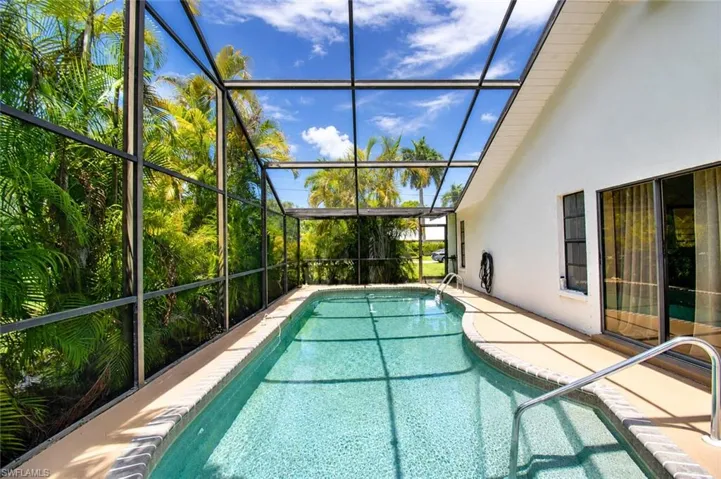 Screened-in swimming pool featuring a curved design and integrated steps