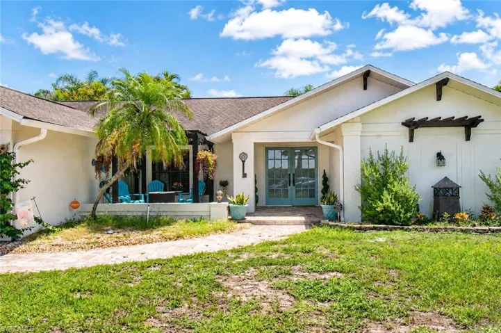 Single-story residence featuring a light-colored stucco exterior with dark brown roof shingles