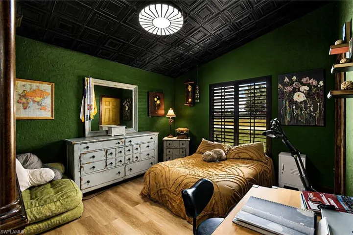 Actual current room vaulted ceiling with black panels, wood-finish flooring, and a window featuring dark louvered shutters