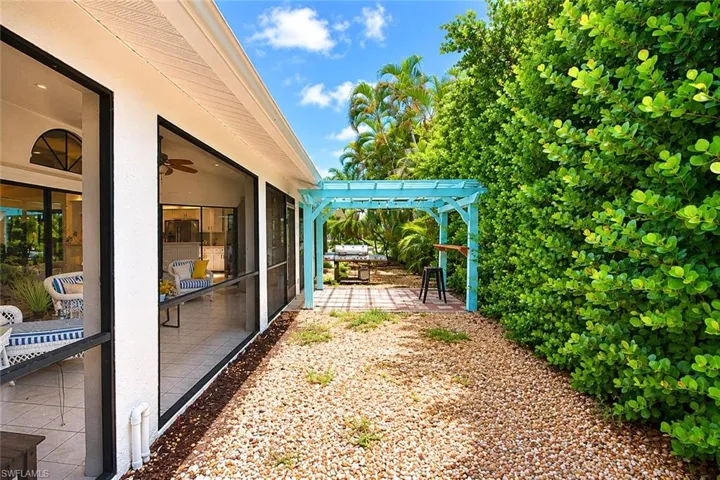 back yard featuring a gravel pathway, mature privacy landscaping, and a light blue pergola with a built-in bar