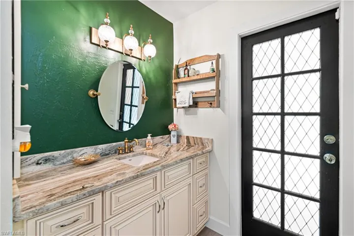 Vanity area featuring a single basin sink, brass-finish faucet, and a stone countertop