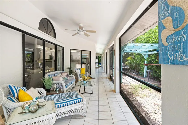 Expansive screened porch featuring white tile flooring, multiple sliding glass doors, a vaulted ceiling, and a ceiling fan