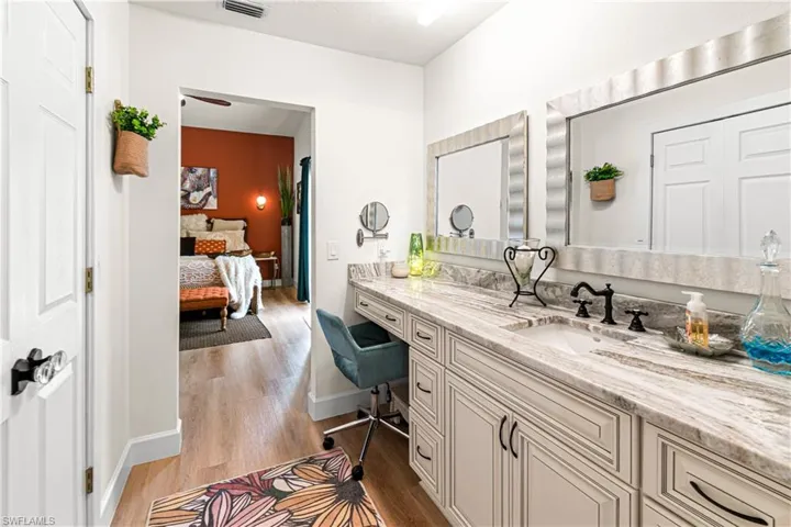Vanity with integrated sink, stone countertop, matte black faucet, and framed mirrors