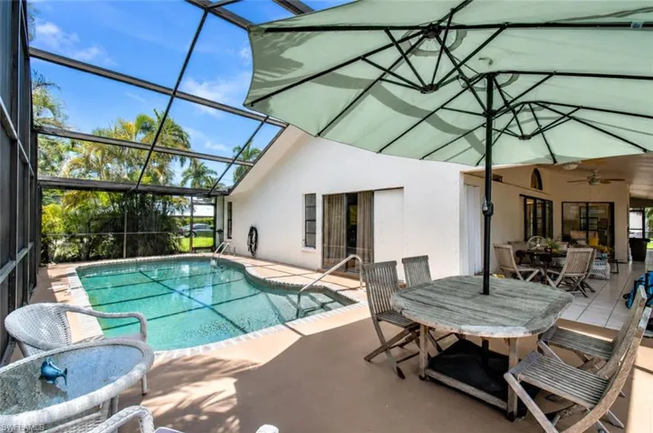 Screened lanai featuring a curved swimming pool, expansive paved patio, and covered outdoor living space