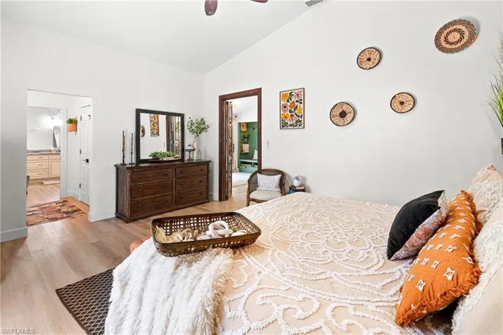 Vaulted ceiling bedroom featuring wood-finish flooring