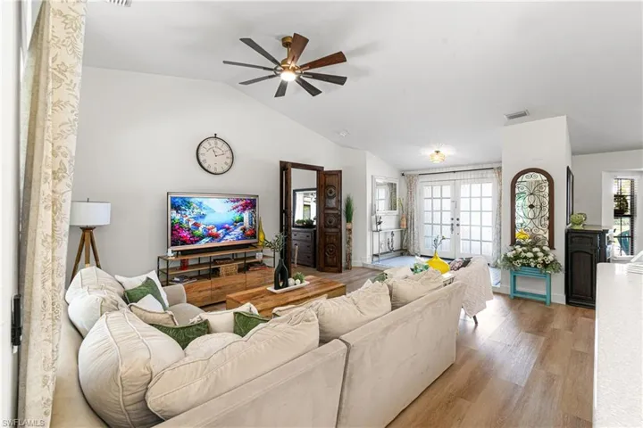 Spacious living area featuring vaulted ceilings, wood-finish flooring, and a ceiling fan with integrated lighting