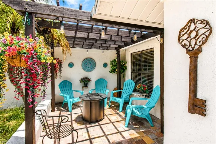 Private patio area featuring a slatted wood pergola, brick paver flooring, string lighting, and a window with horizontal blinds