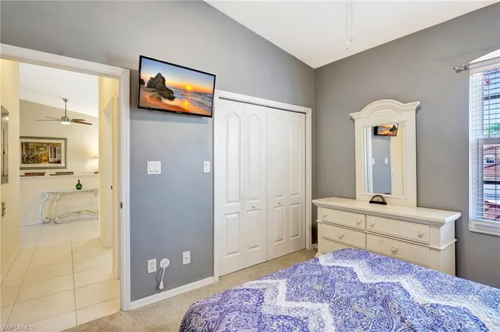 Bedroom featuring lofted ceiling, a closet, light tile patterned flooring, and baseboards