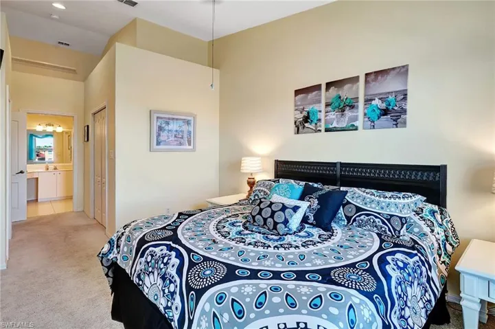 Carpeted bedroom featuring connected bathroom, visible vents, and a closet