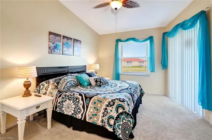 Carpeted bedroom with vaulted ceiling, baseboards, and ceiling fan