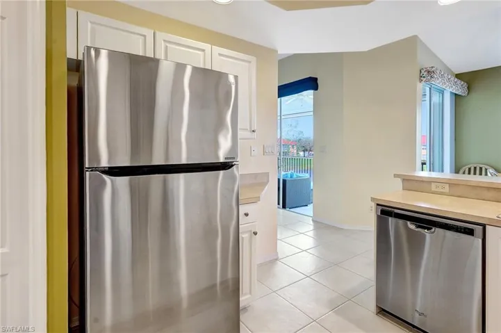 Kitchen featuring baseboards, appliances with stainless steel finishes, light countertops, white cabinetry, and light tile patterned flooring
