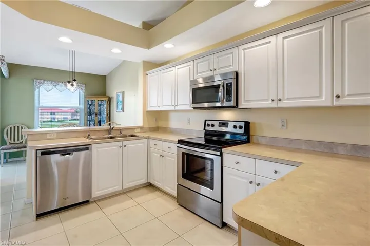 Kitchen featuring recessed lighting, stainless steel appliances, a peninsula, a sink, and light countertops