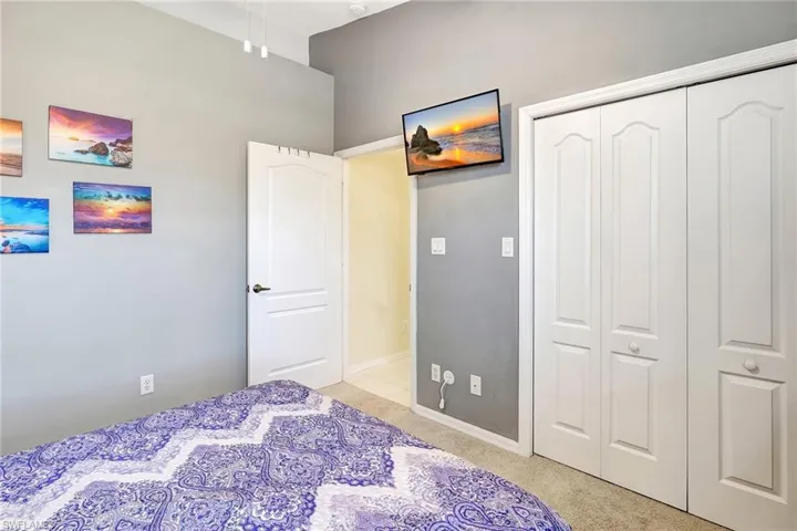 Bedroom with a closet, light colored carpet, and baseboards