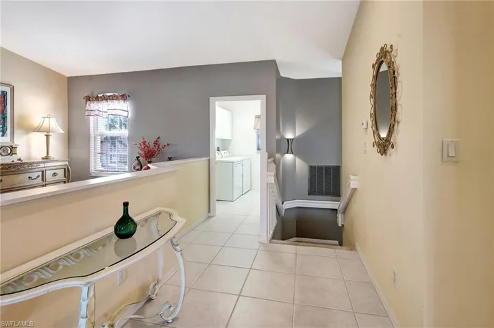 Corridor featuring light tile patterned floors, baseboards, visible vents, and separate washer and dryer