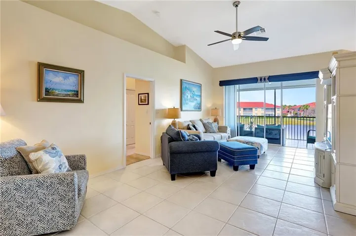 Living room featuring lofted ceiling, light tile patterned floors, a ceiling fan, and baseboards