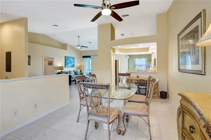 Dining space featuring light tile patterned floors, electric panel, visible vents, a ceiling fan, and lofted ceiling