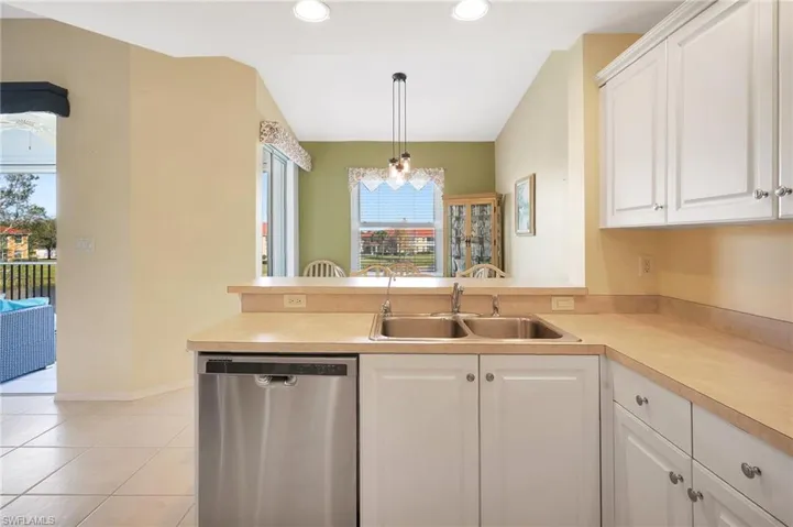 Kitchen featuring white cabinets, a sink, stainless steel dishwasher, and light tile patterned floors