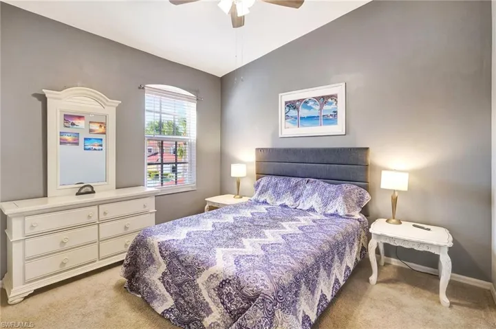 Bedroom with lofted ceiling, baseboards, a ceiling fan, and light colored carpet