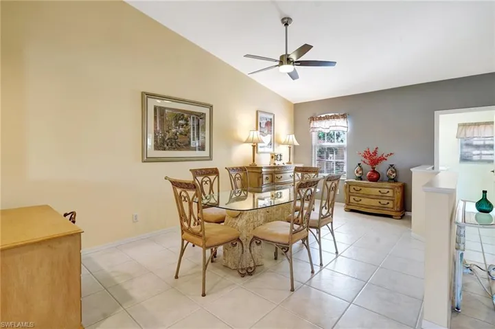 Dining room with lofted ceiling, ceiling fan, light tile patterned floors, and baseboards