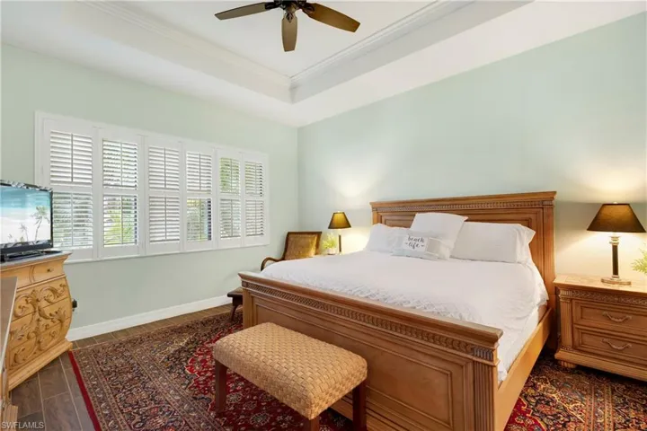 Bedroom featuring ceiling fan, a tray ceiling, and ornamental molding
