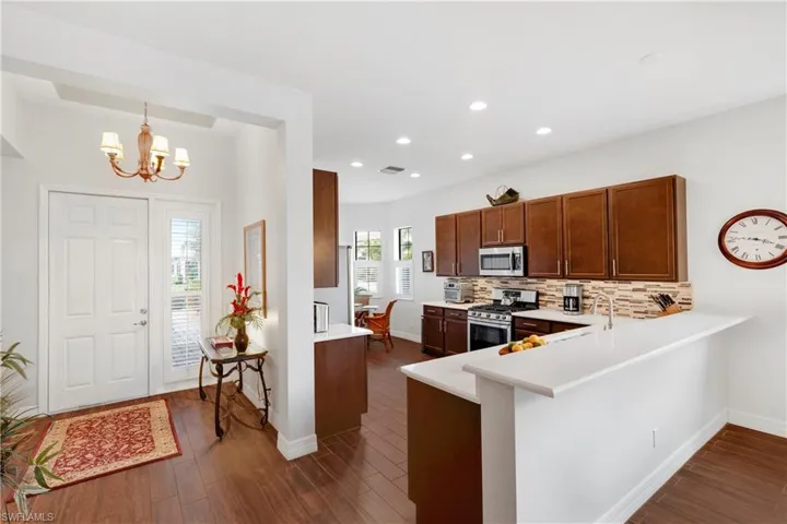 Kitchen with stainless steel appliances, decorative backsplash, and dark hardwood / wood-style floors