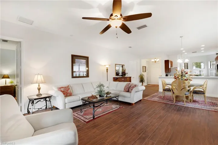 Living room featuring built in features, ceiling fan with notable chandelier, and dark hardwood / wood-style floors