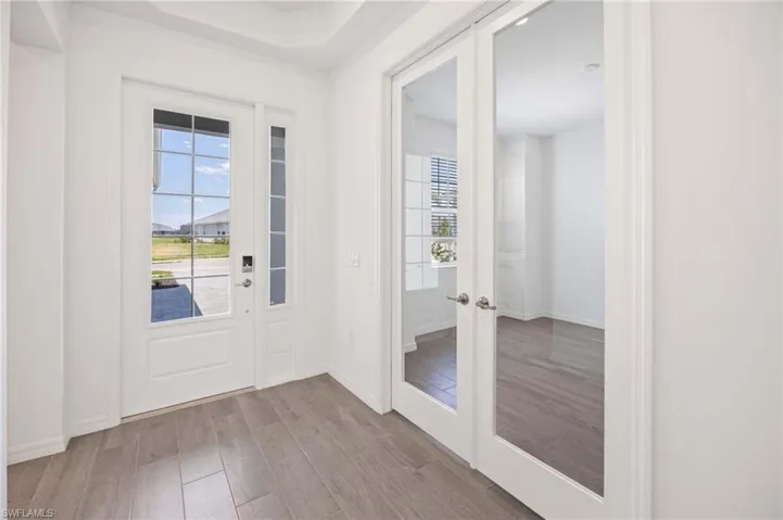 Doorway with baseboards, french doors, and wood finished floors