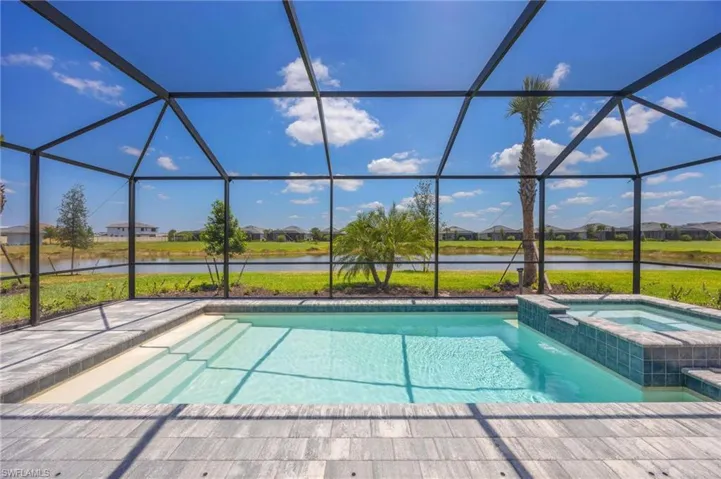 View of pool with a water view, a patio area, a lanai, and a pool with connected hot tub