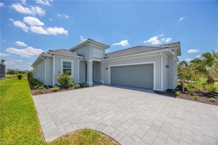 View of front of home with a tiled roof, a garage, decorative driveway, a front lawn, and stucco siding