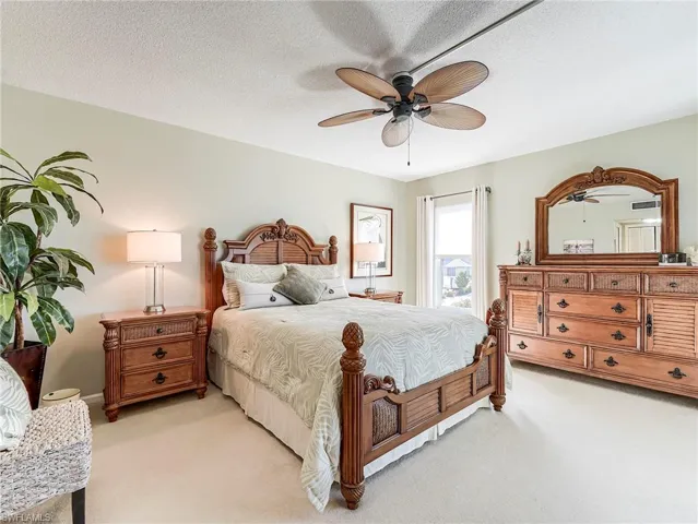 Bedroom featuring light carpet, ceiling fan, and a textured ceiling