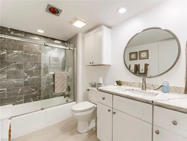 Full bathroom with vanity, shower / bath combination with glass door, light wood-style floors, and recessed lighting