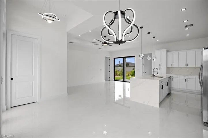 Open-concept living area featuring a modern kitchen with a waterfall island, white cabinetry, and stainless steel appliances