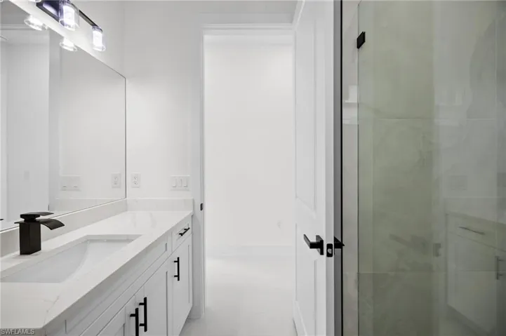 Bathroom vanity featuring a single integrated sink, stone-finish countertop, and black fixtures