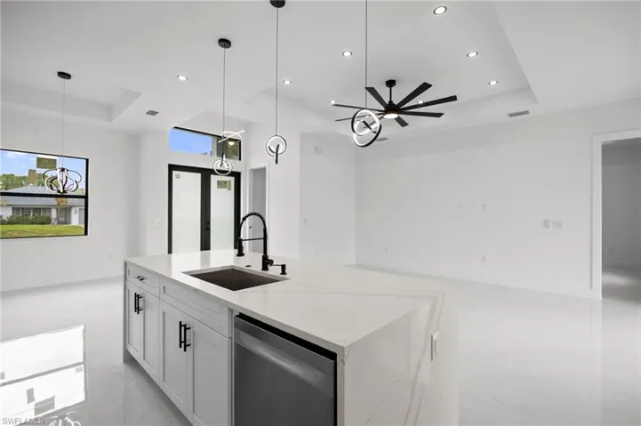 Contemporary kitchen island featuring a waterfall countertop, undermount sink with a gooseneck faucet, and integrated dishwasher