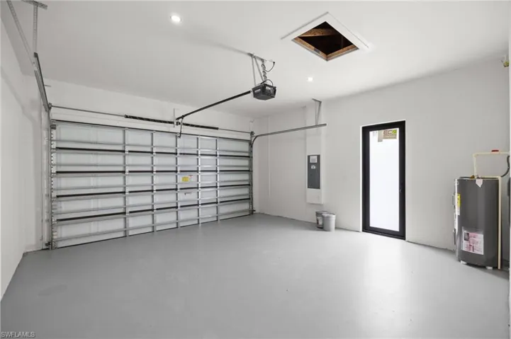 Spacious garage with a sectional overhead door, gray finished flooring, recessed lighting, and a black-framed access door