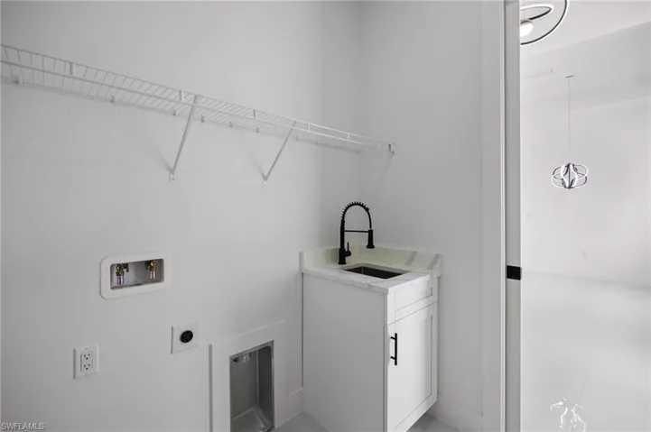 Utility room featuring a built-in sink with a black matte faucet, white cabinetry, and a light-toned countertop